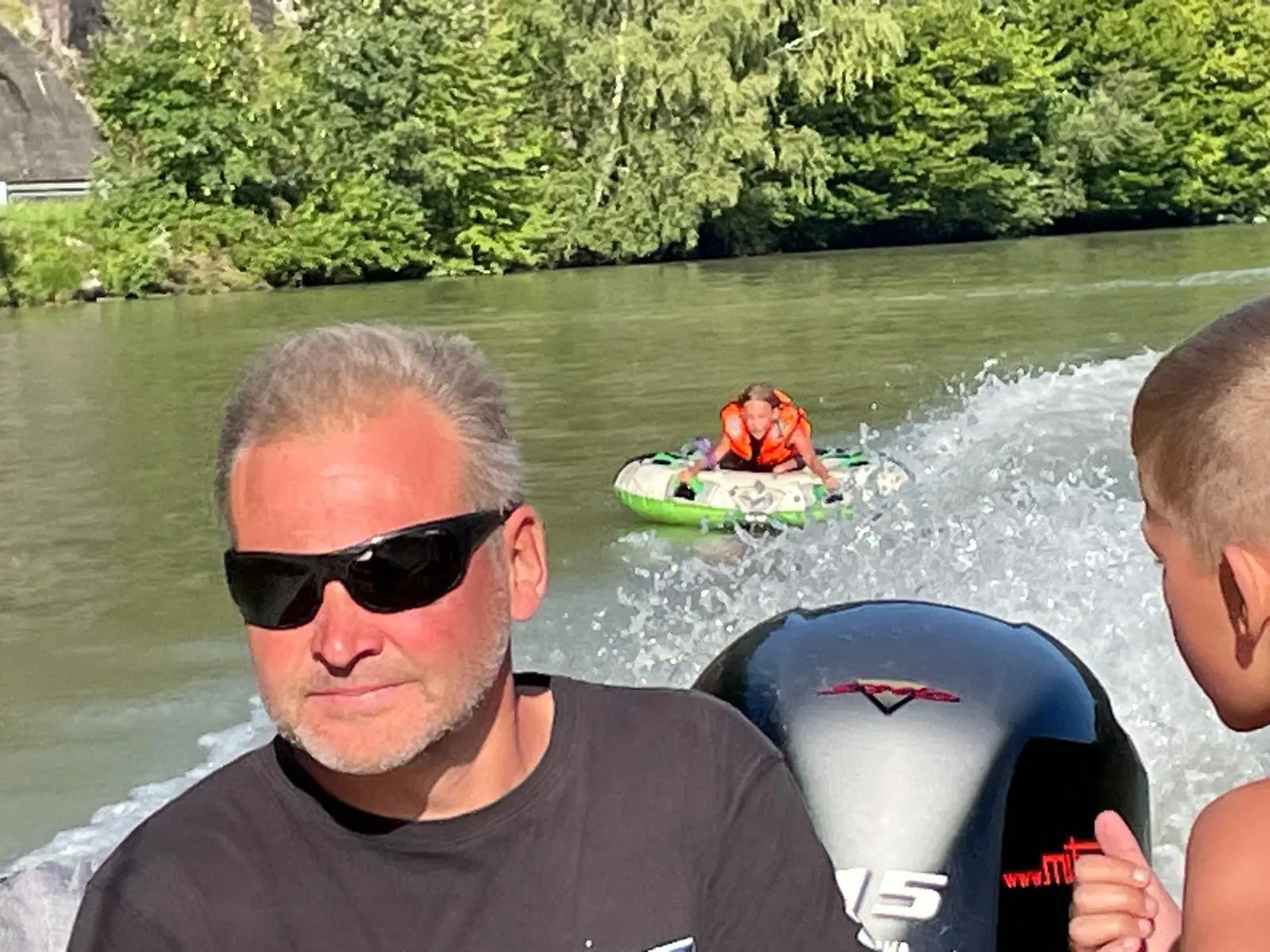 View from the boat: child being towed on a tube across the Danube