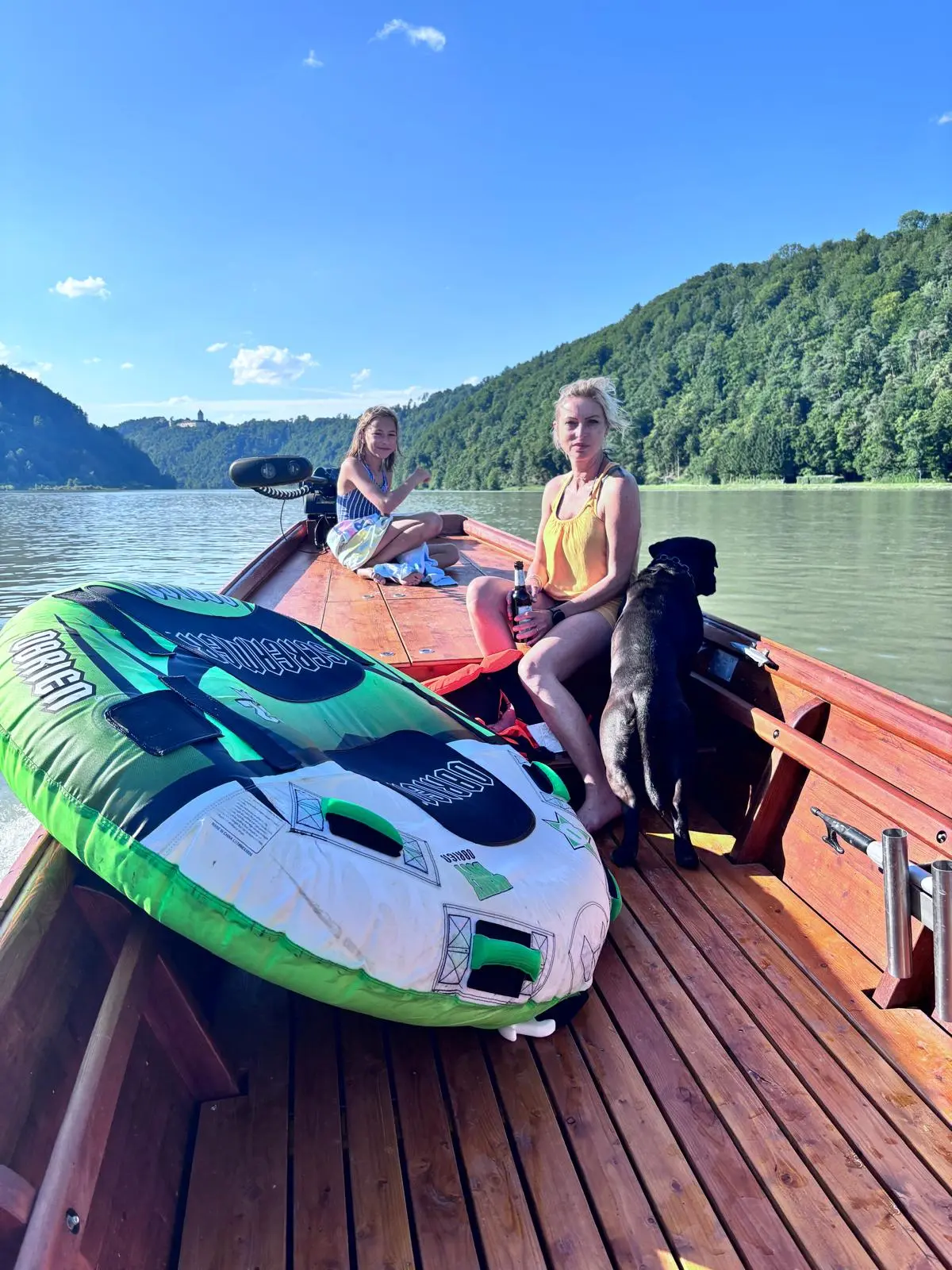 Family with dog relaxing on the wooden boat, tube ready for action