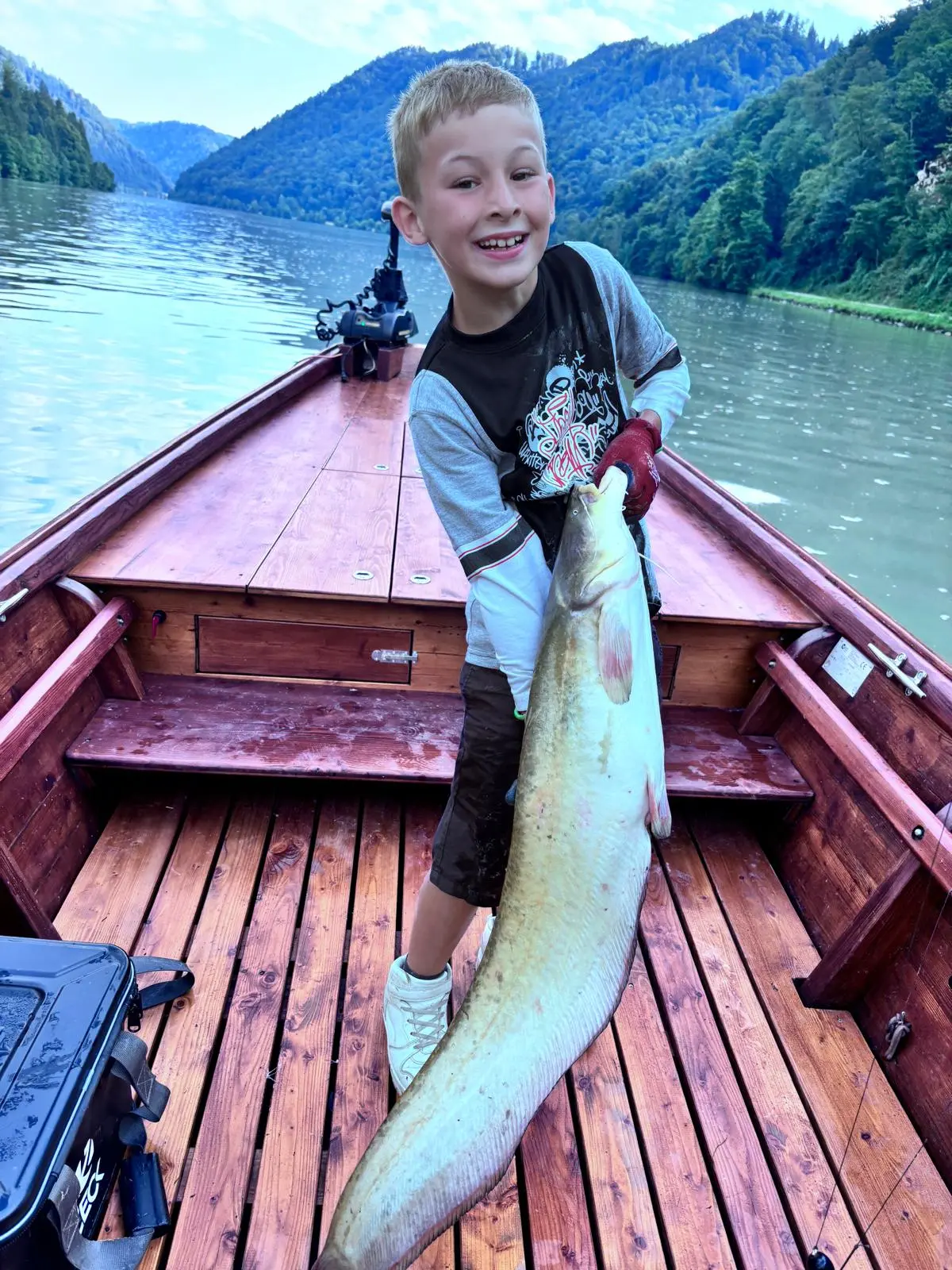 Boy holding a huge catfish, almost as big as himself