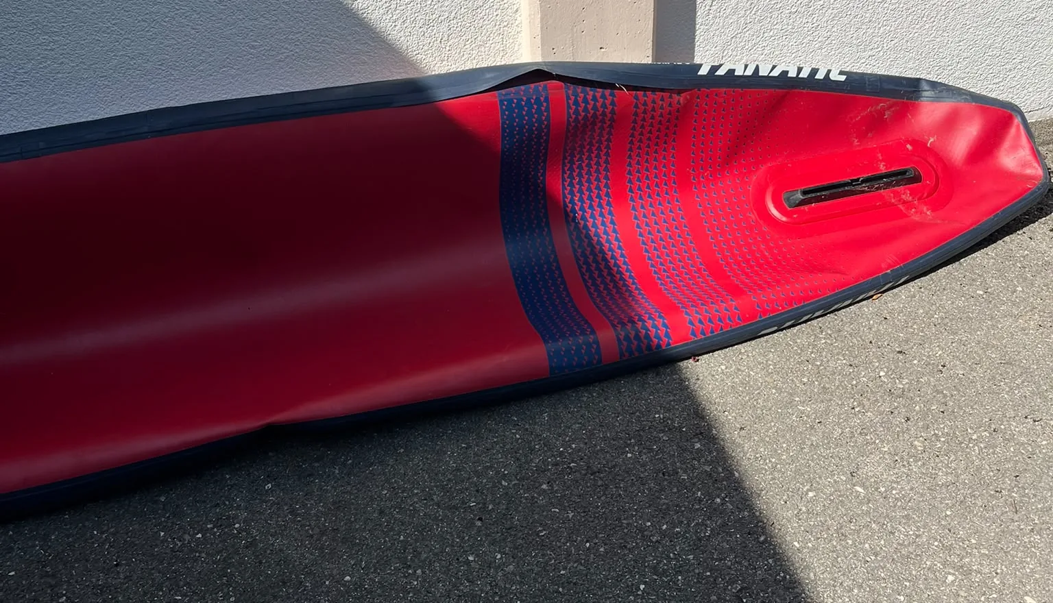 Red inflatable kayak with damage on the side wall