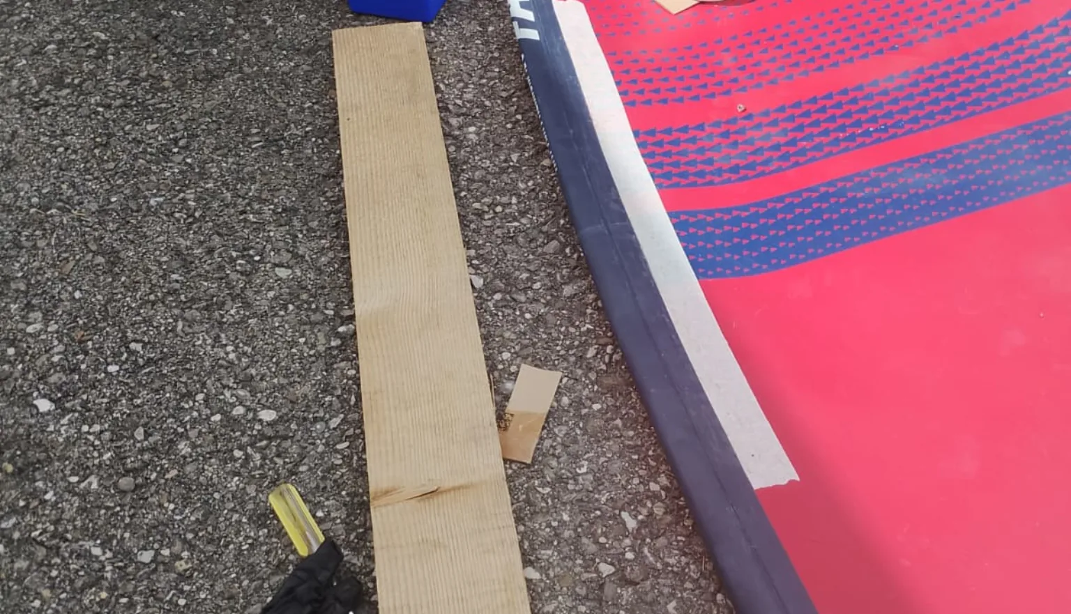 Repair on the rail of a red SUP board with a repair kit